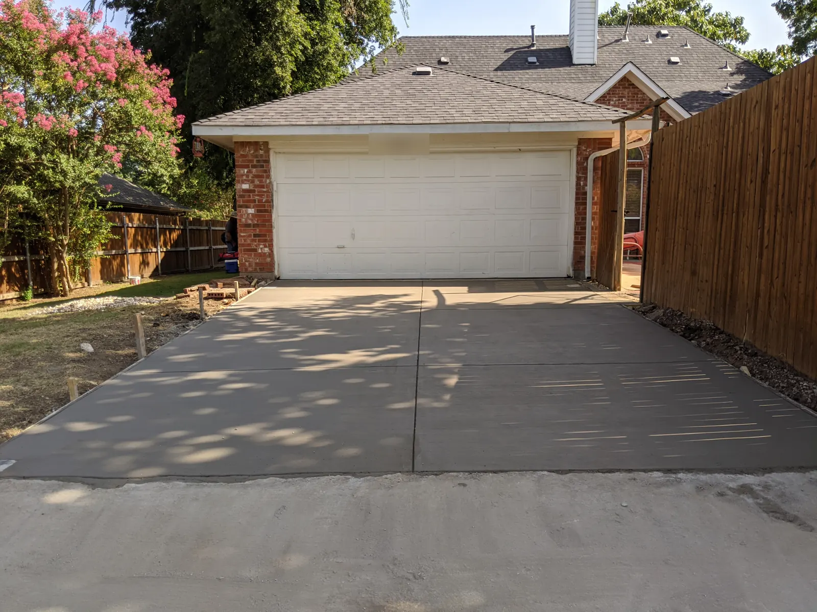 New broom-finish concrete driveway in front of a detached two-car garage