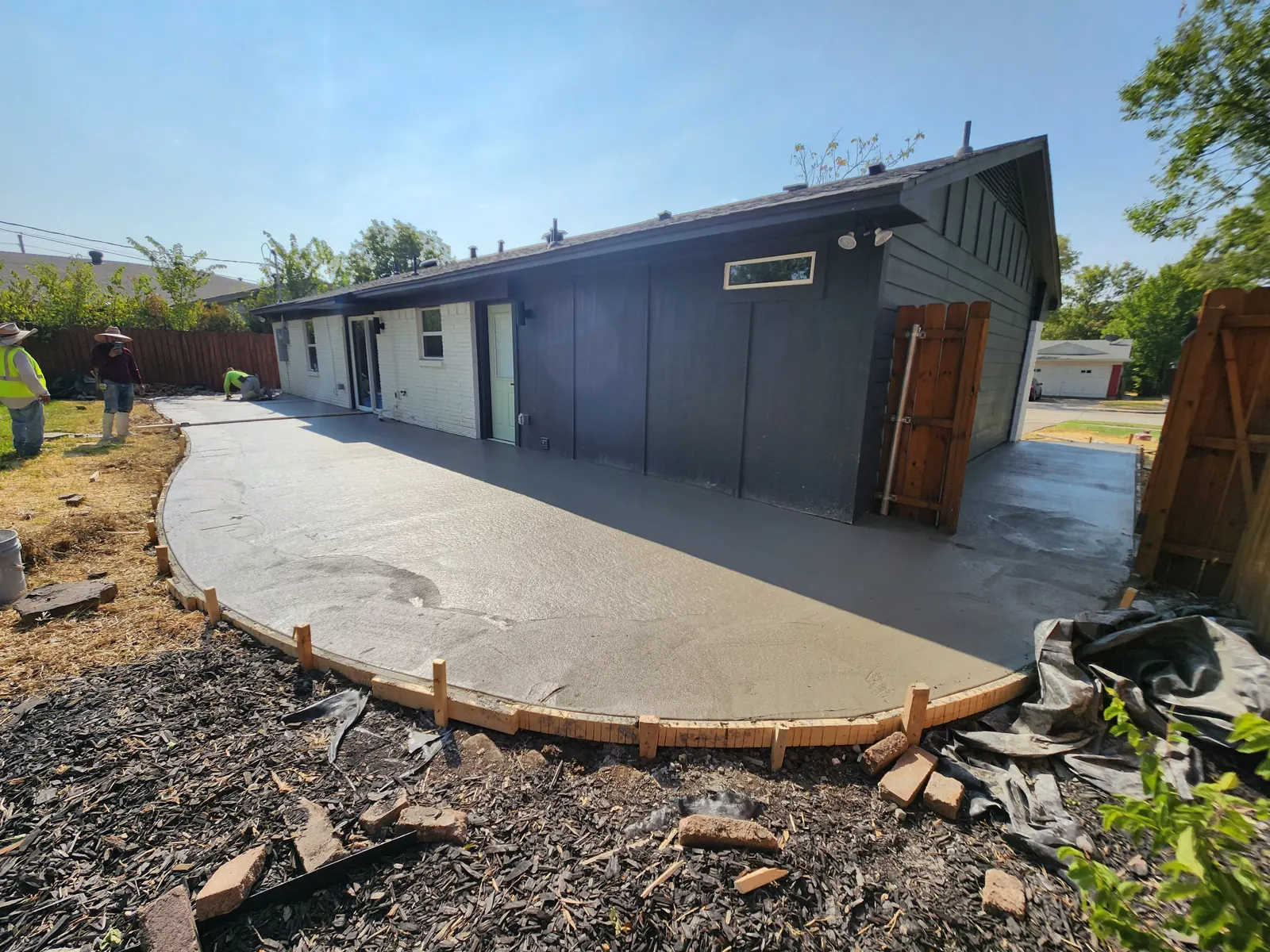 Large curved back patio freshly poured along a modern painted home