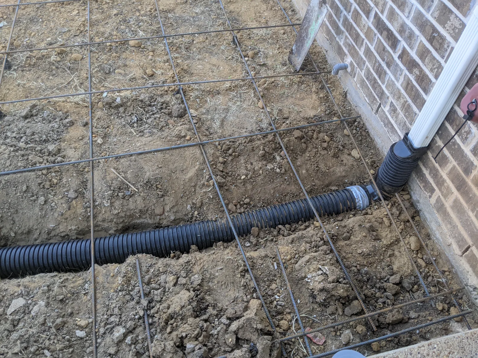 Downspout drain pipe run under the rebar before a patio pour