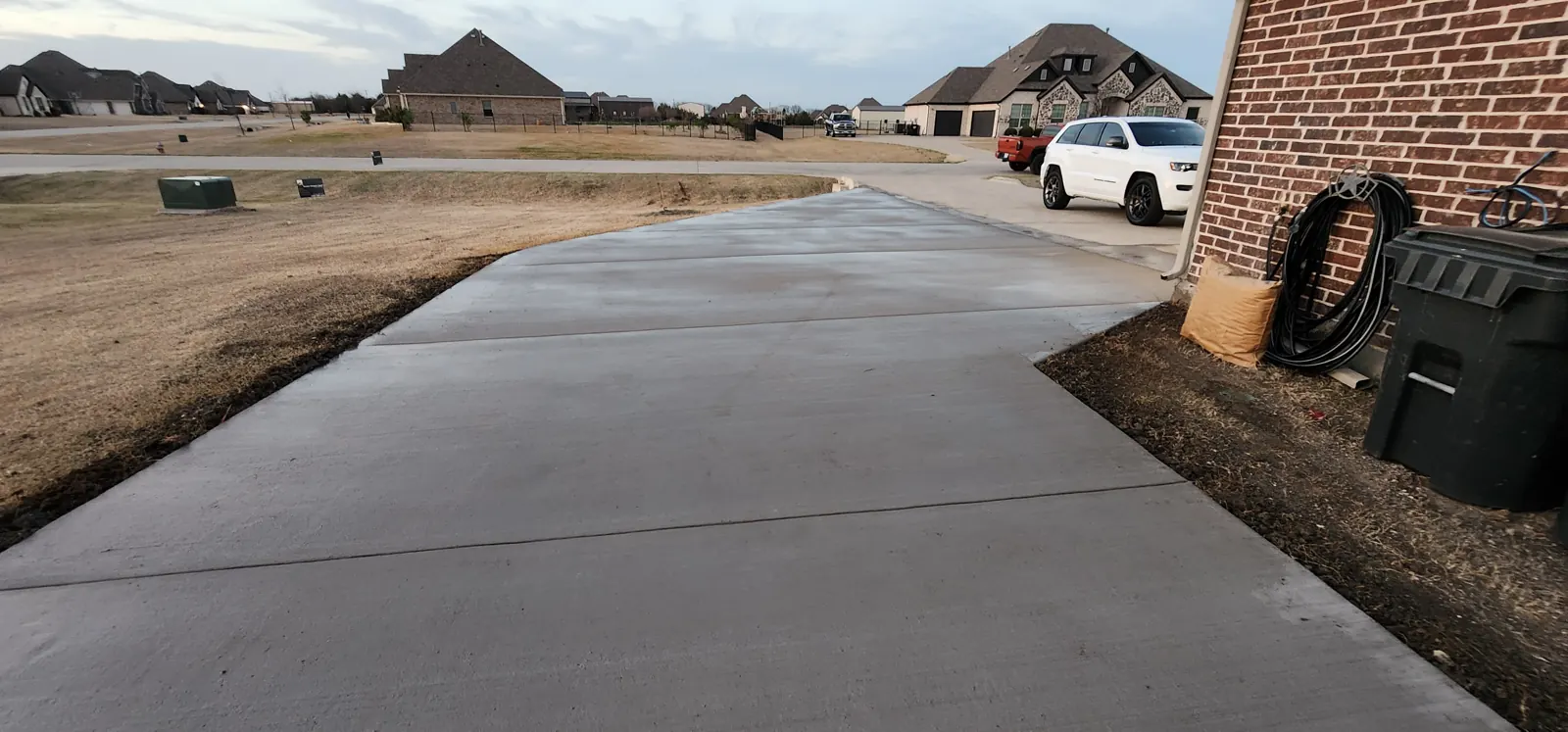 Widened concrete driveway with clean control joints next to a brick home