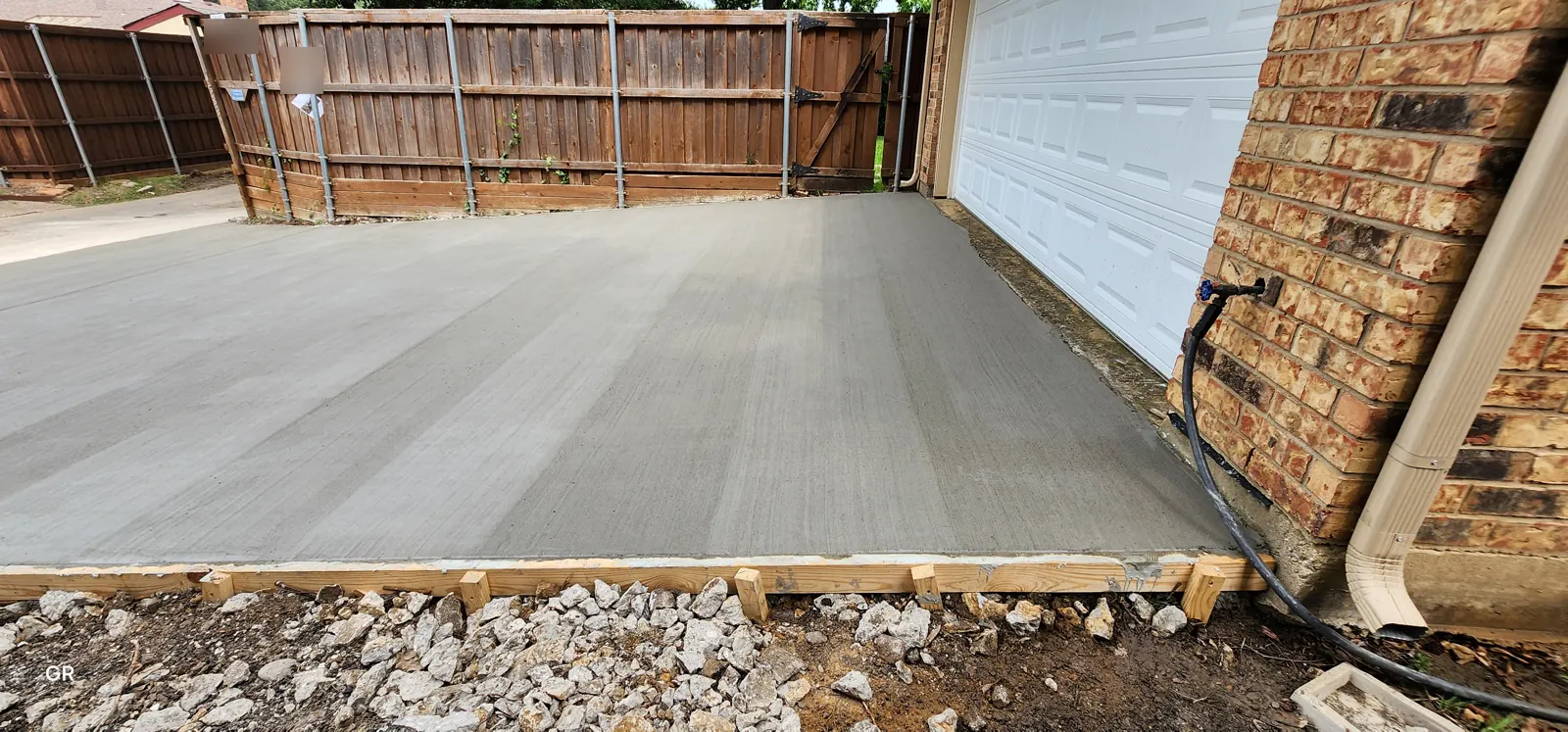 Freshly finished concrete garage apron with forms and base rock still visible