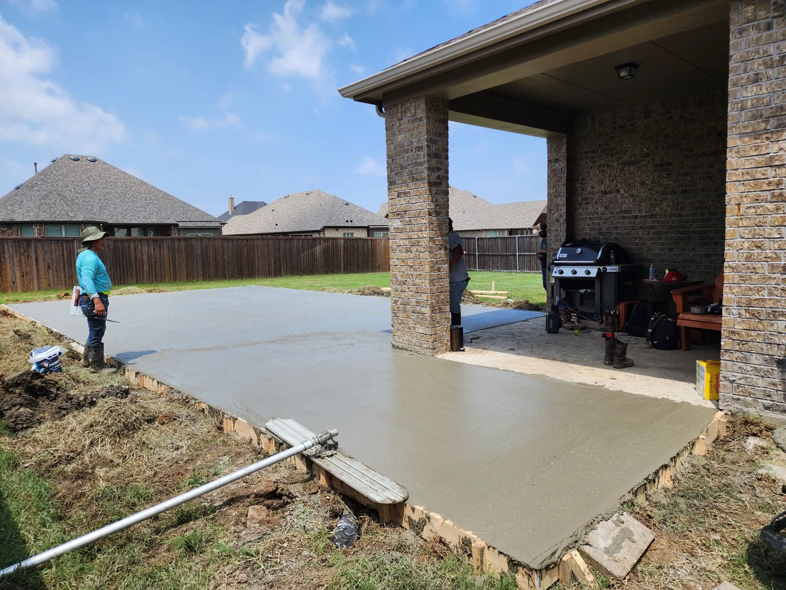 Freshly screeded patio slab extending from a covered porch