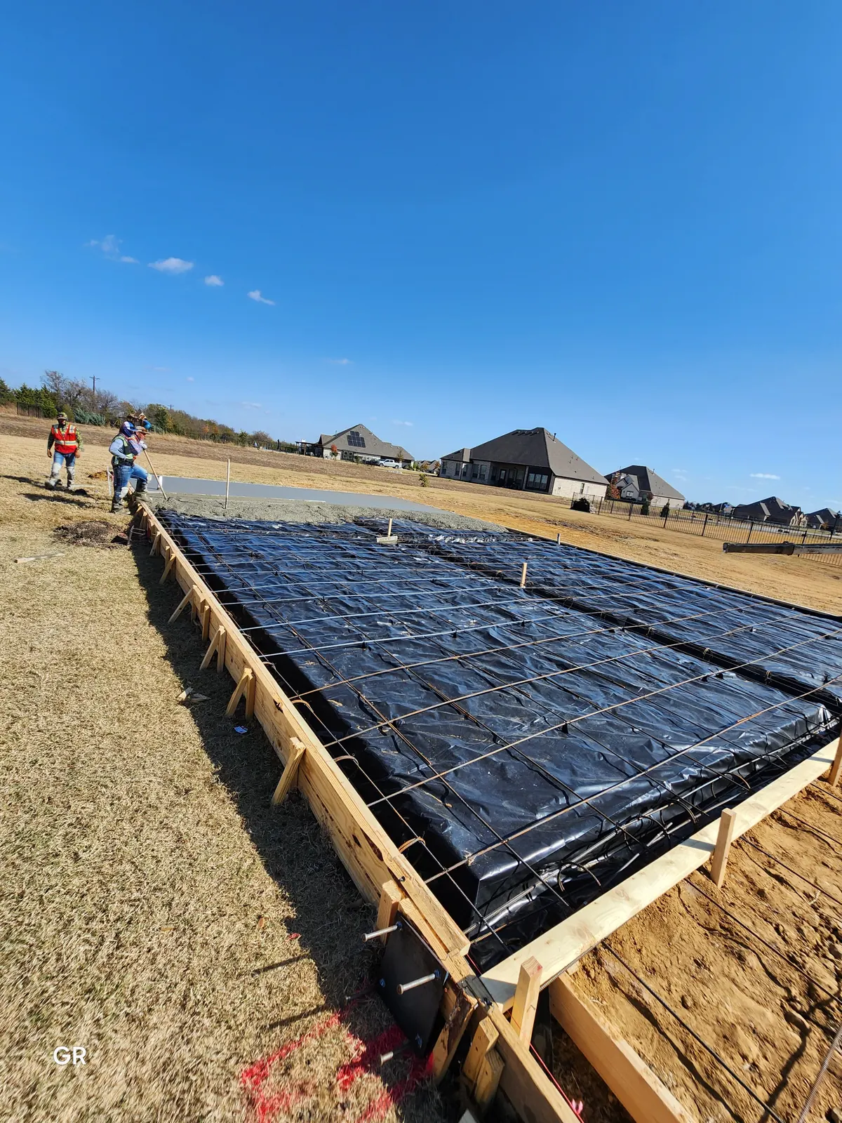 Shop slab forms with vapor barrier and rebar, pour starting at the far end