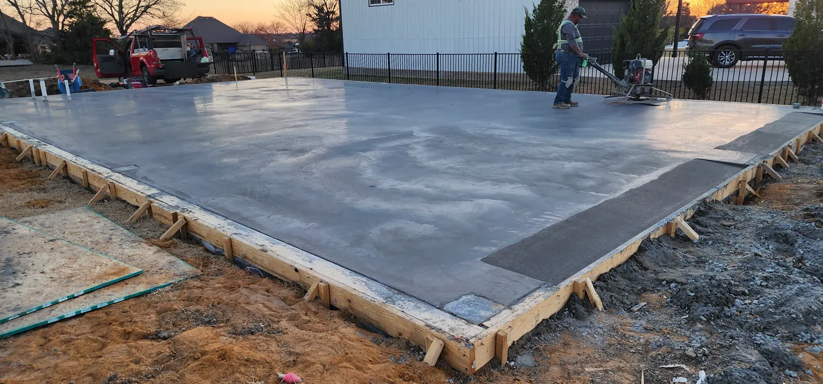 Crew power-troweling a large shop slab at sunset