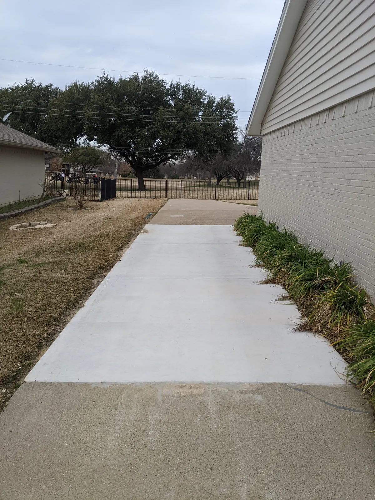 New concrete side walkway beside a painted brick home