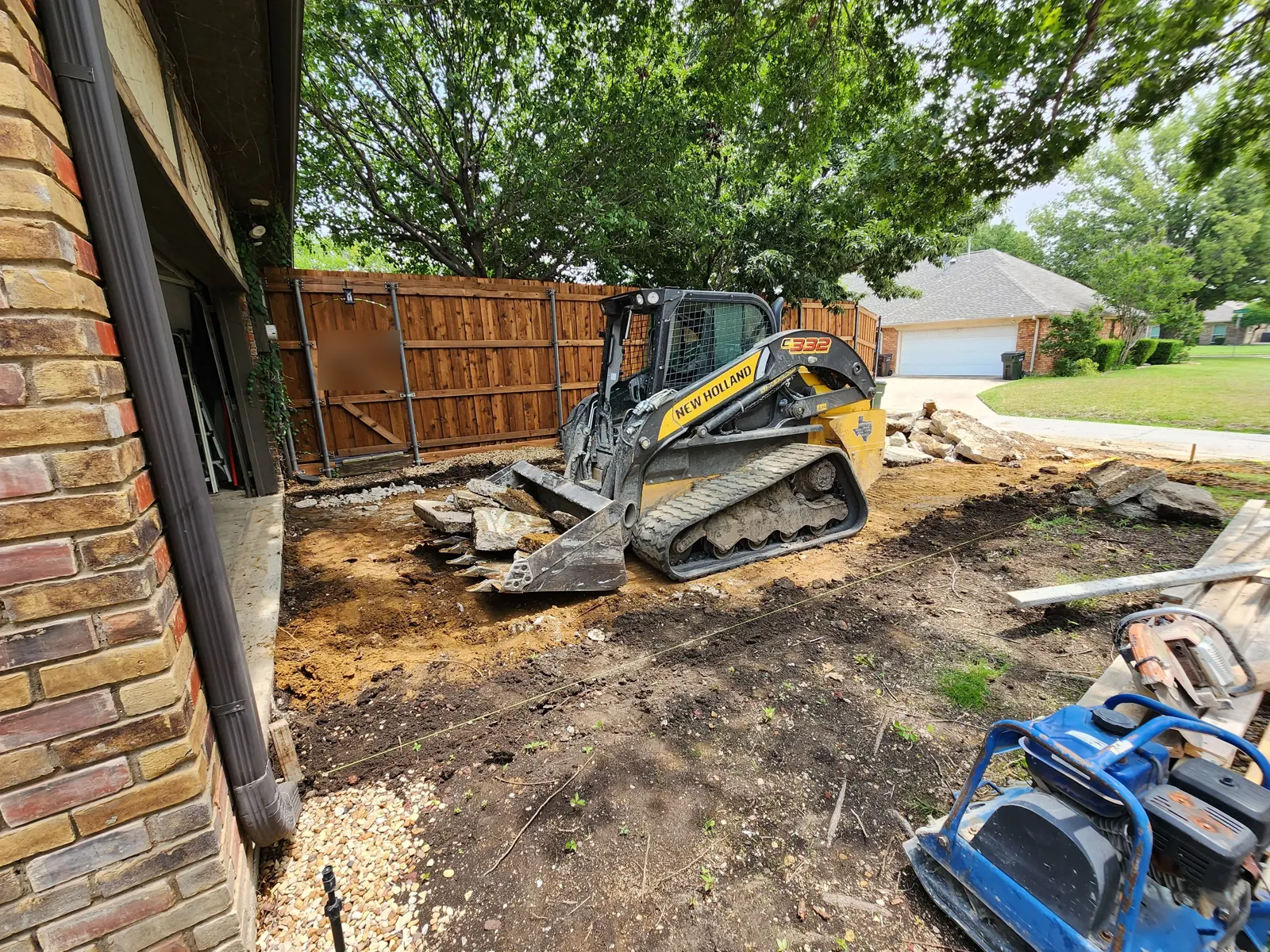 Track loader carrying broken concrete out of a driveway