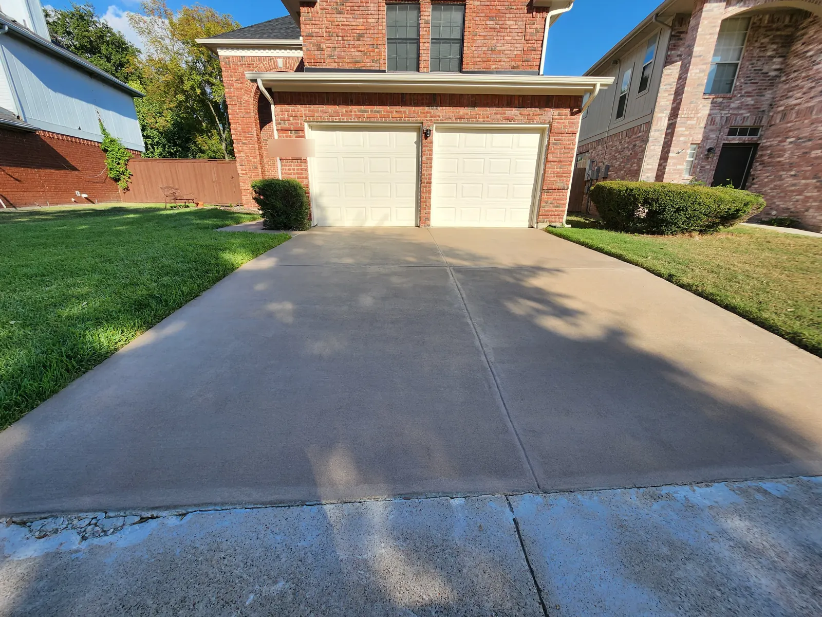Replaced two-car concrete driveway in front of a brick home