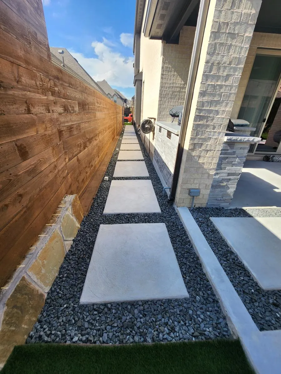 Side-yard stepping-stone walkway with black gravel, stone veneer wall and outdoor kitchen counter