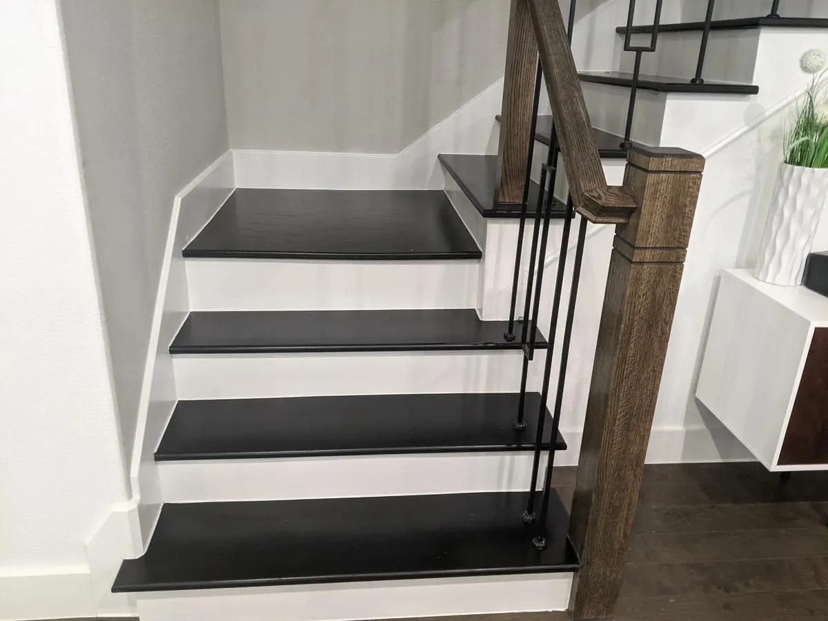 Interior staircase remodel with black treads, white risers and a stained wood handrail