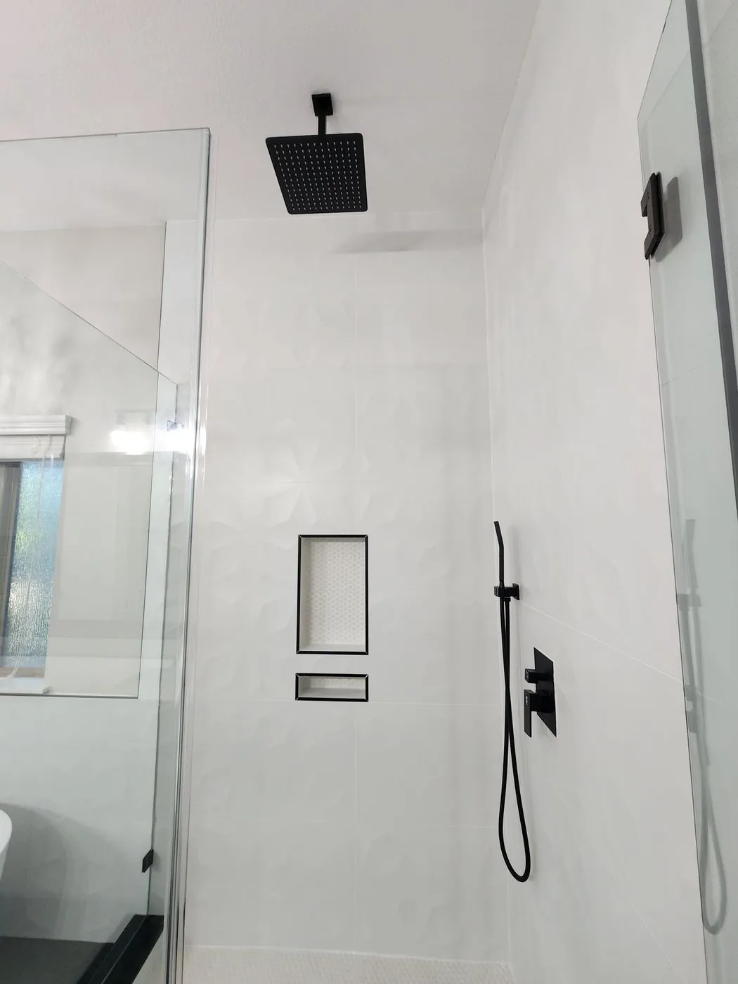 Contemporary walk-in shower with white geometric tile, matte black rainfall head and recessed niches