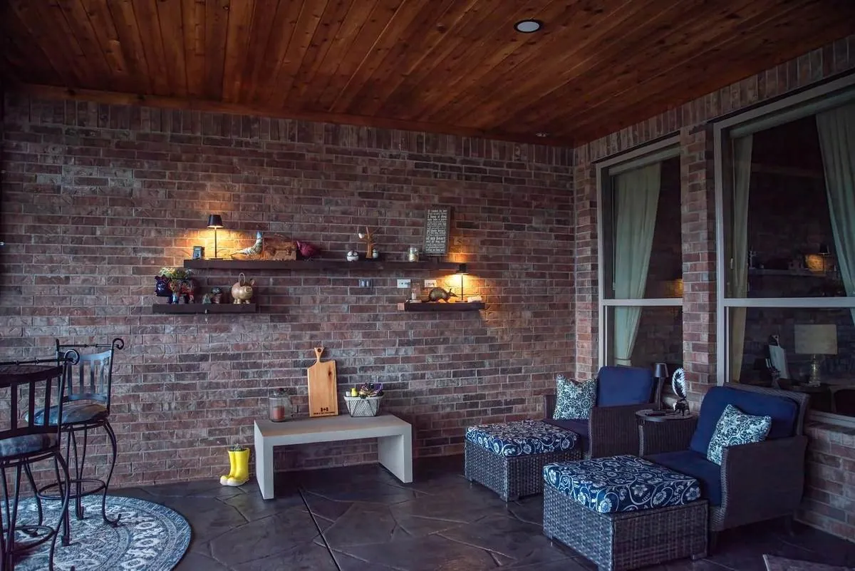 Covered patio living area with brick wall and warm lighting