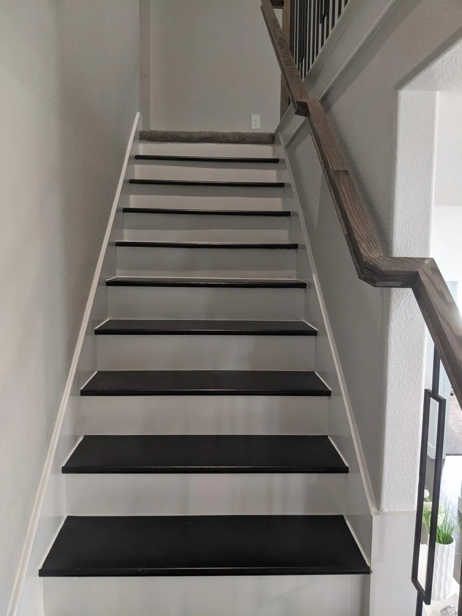 Refinished staircase with black treads, white risers, iron balusters and a wood newel post
