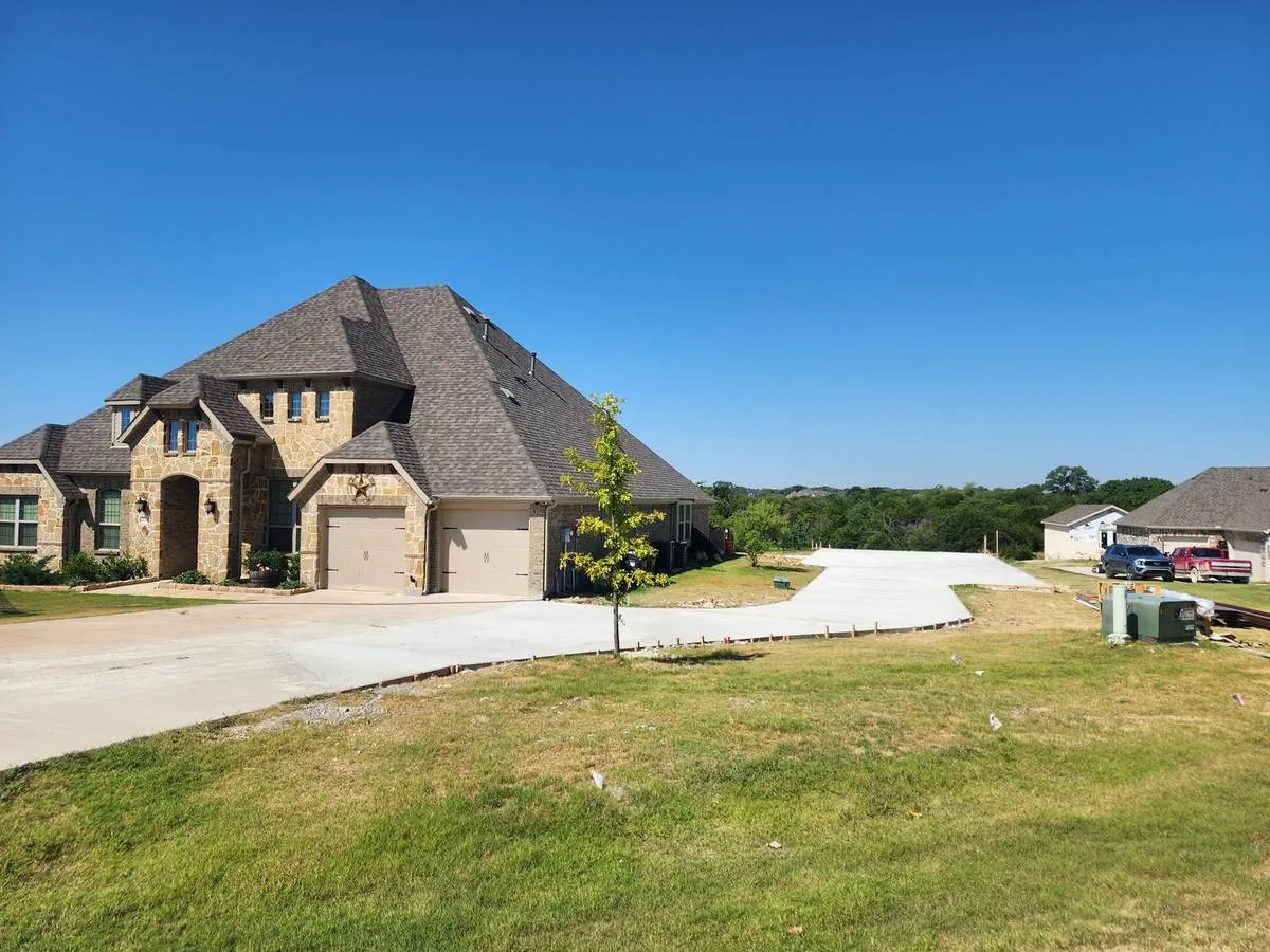 Wide finished concrete driveway at a stone-and-brick estate home