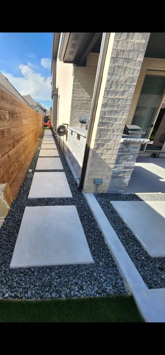 Large concrete paver walkway set in black gravel beside a home
