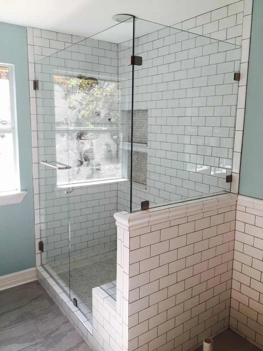 White subway tile walk-in shower with corner bench and frameless glass door