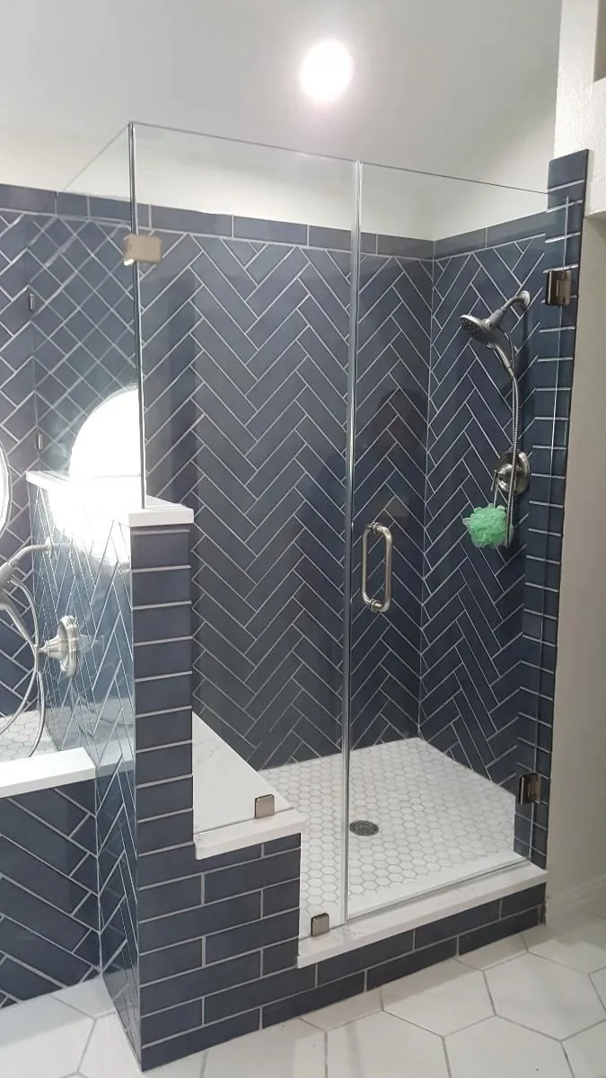 Walk-in shower with navy herringbone tile, built-in bench and hexagon mosaic floor
