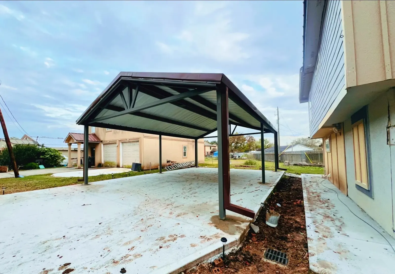 Gable steel carport over a new concrete slab beside a home