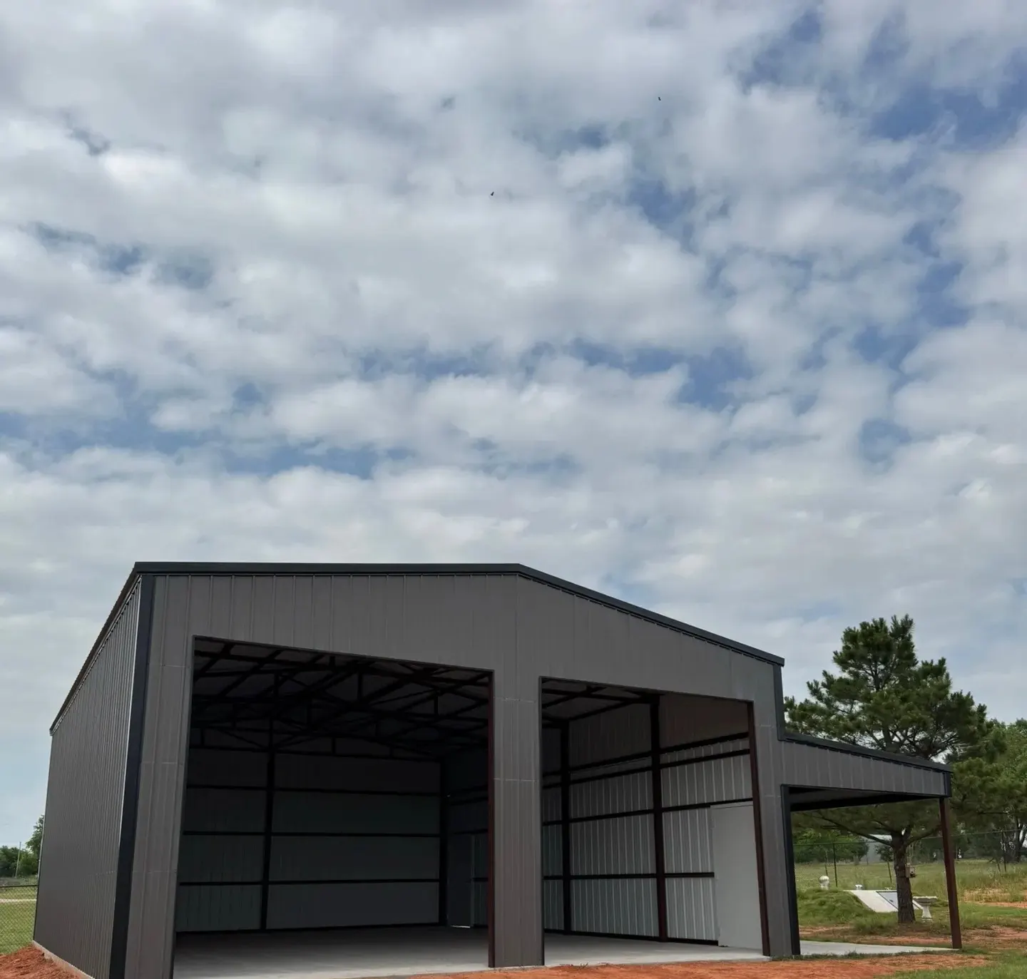 Gray metal garage with two open bays and a side lean-to