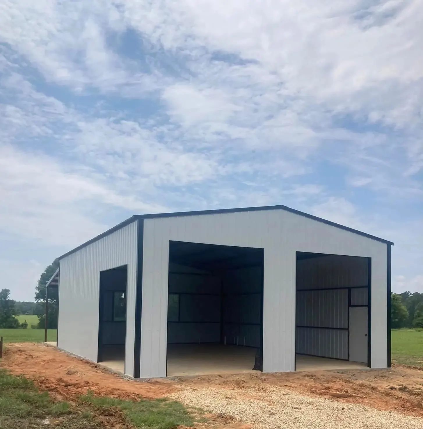 White metal garage with black trim and three open bays on a new slab