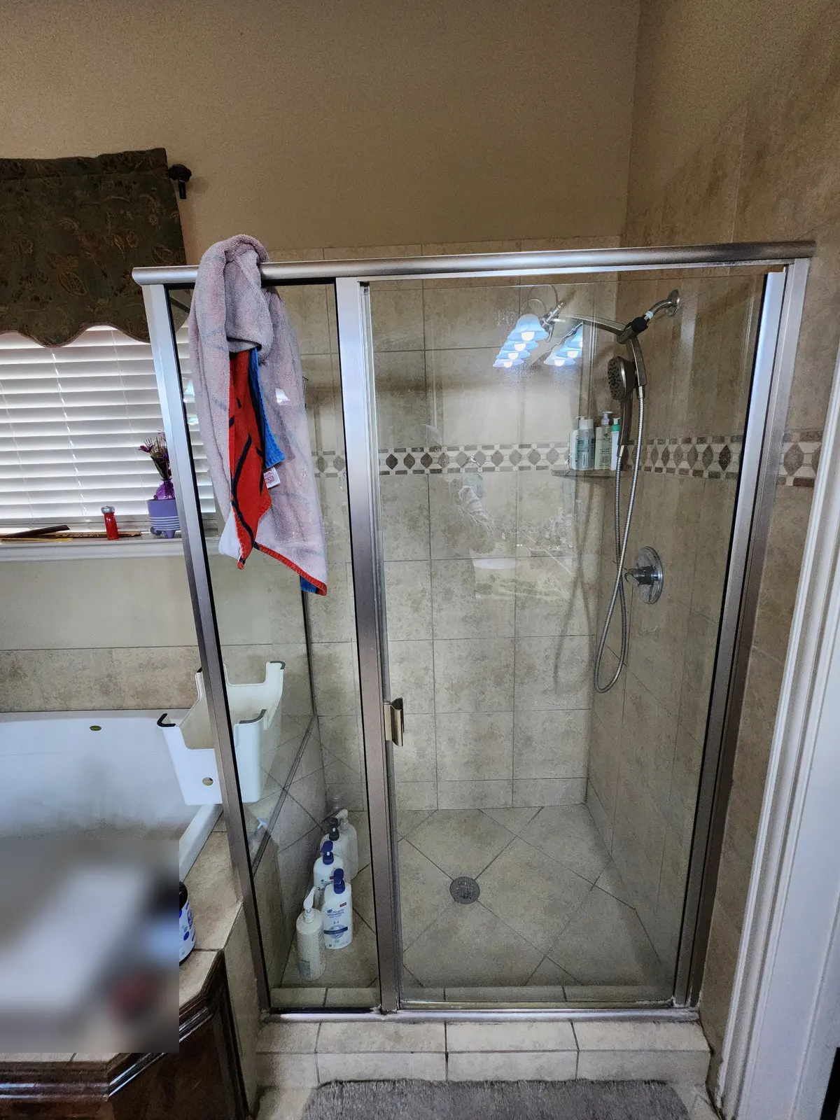 Before: Dated framed glass shower with beige tile and a decorative border