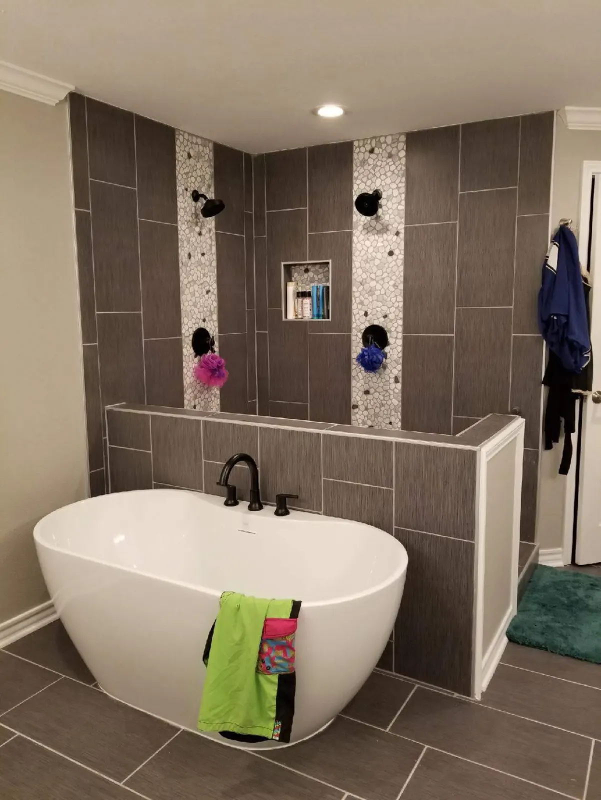 Gray plank tile double shower with pebble accent stripes and a freestanding tub