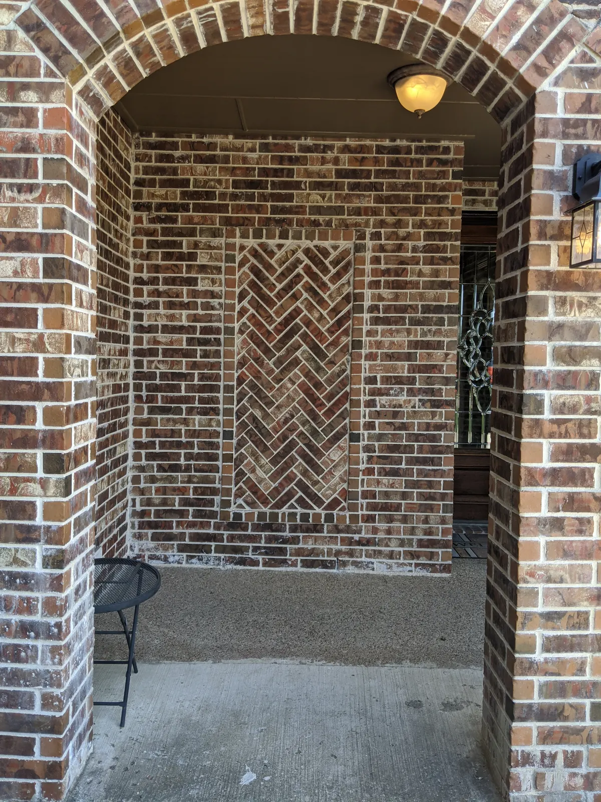 After: Front porch wall with the window bricked in and a herringbone brick panel
