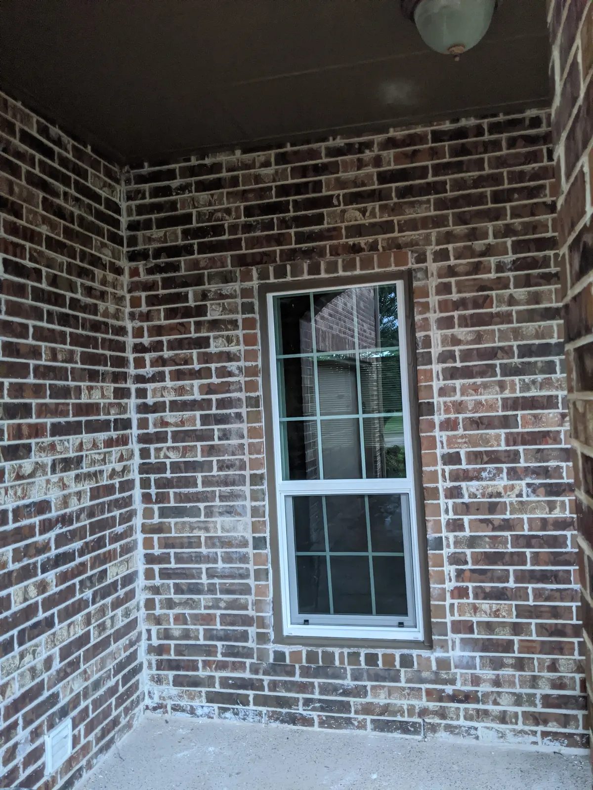 Before: Front porch brick wall with a single window