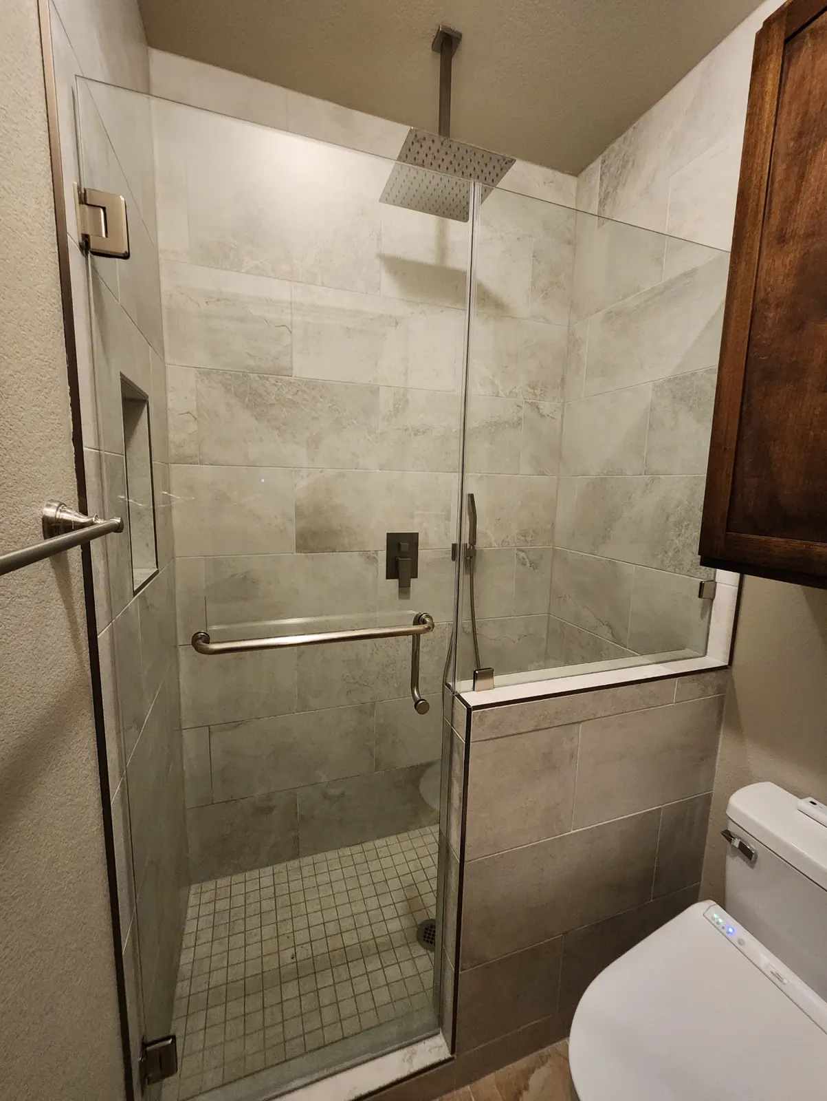 After: Glass walk-in shower with large-format tile, rainfall head and knee wall
