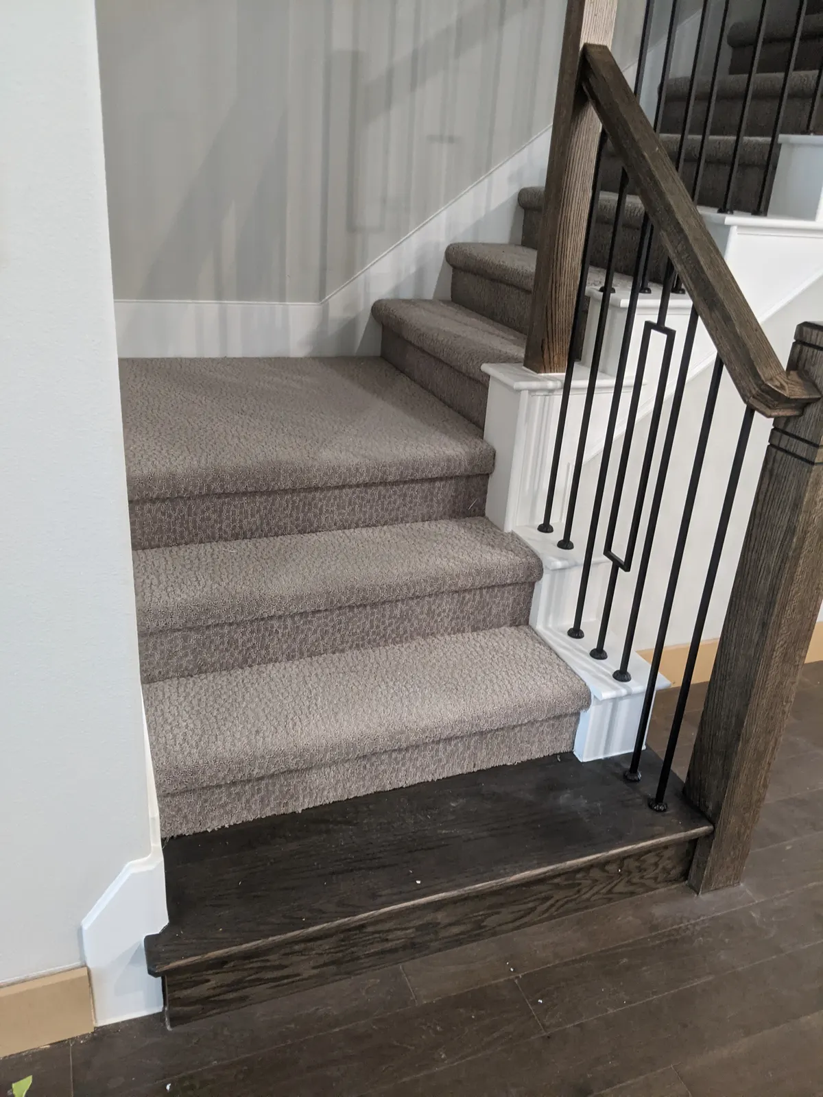 Before: Carpeted lower stairs and landing with iron balusters