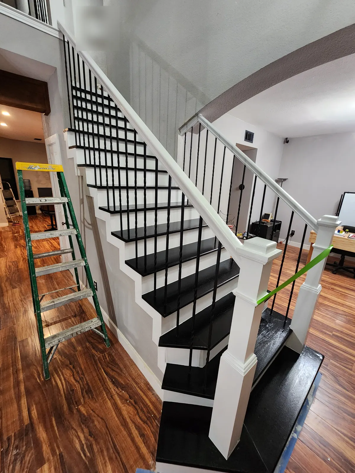 After: Staircase with black treads, white risers, white posts and twisted iron balusters