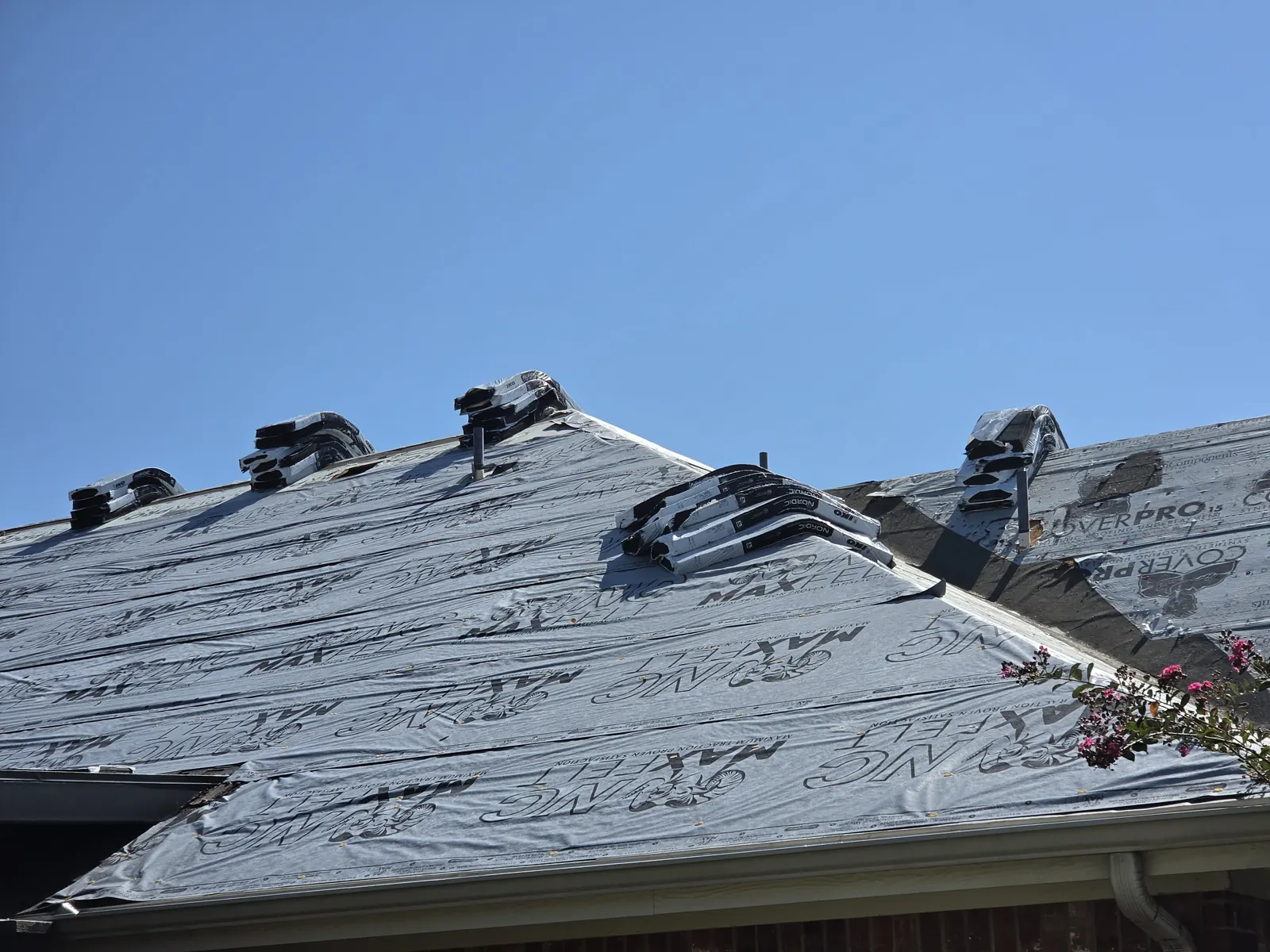 Impact-rated shingle bundles staged along the ridge over new synthetic underlayment