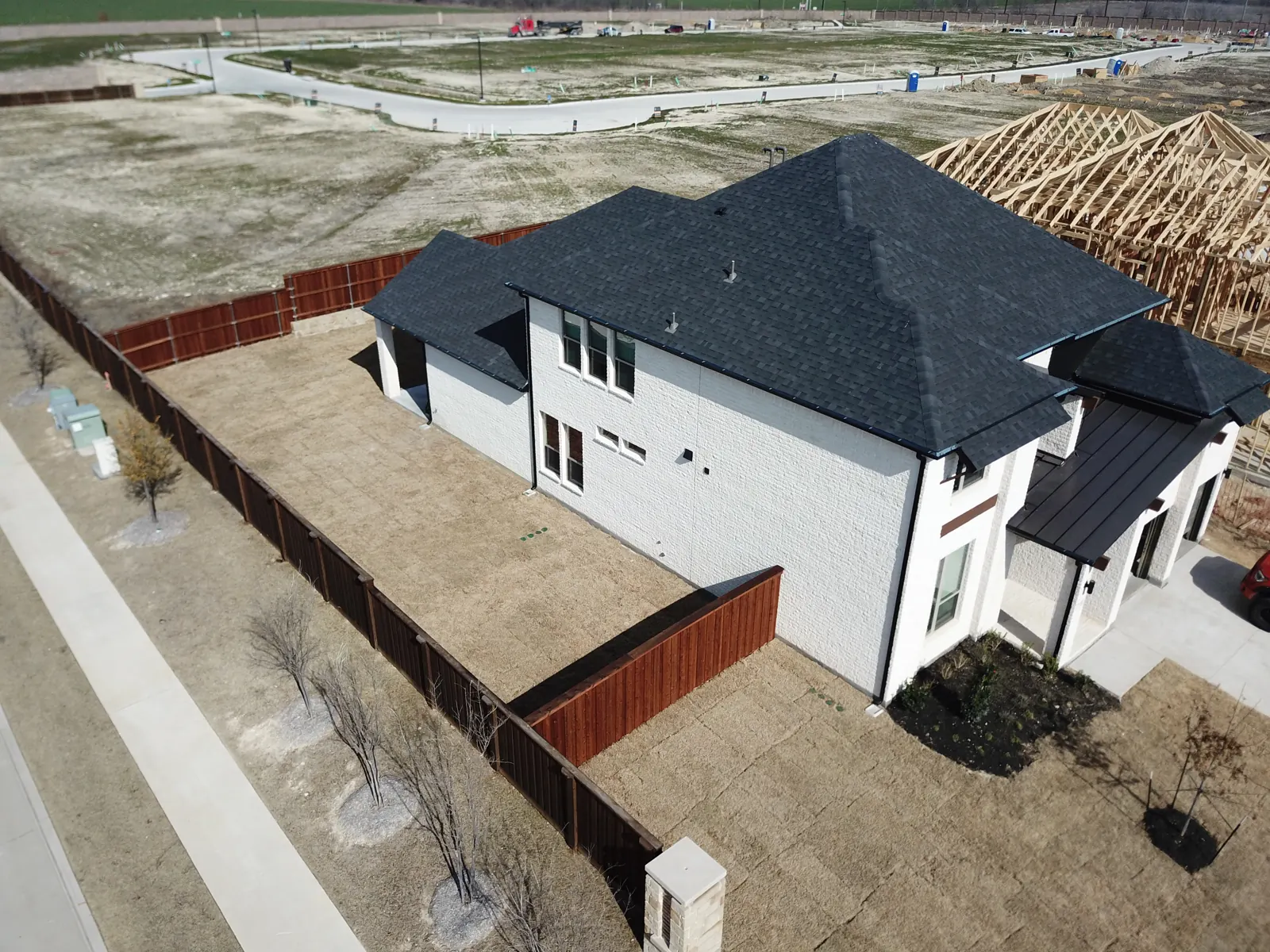 Aerial view of a new two-story home with a charcoal shingle roof and standing-seam metal porch roof