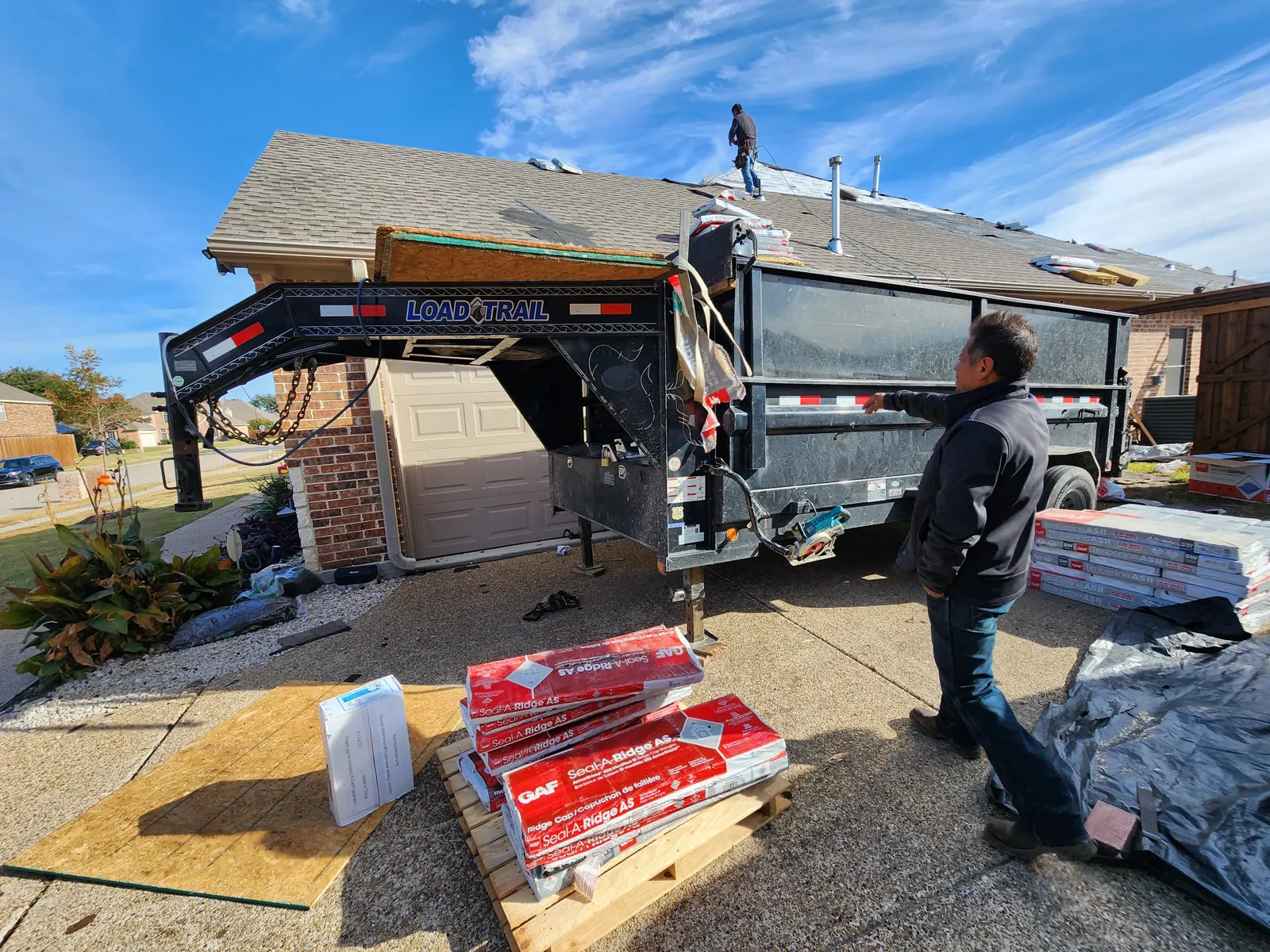 Impact-resistant shingle bundles and ridge cap delivered next to the debris trailer