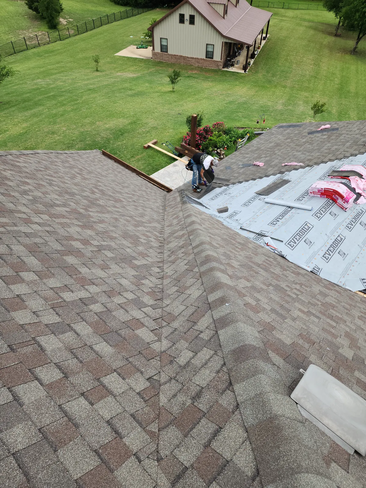 Roofer finishing a closed valley where new shingles meet fresh underlayment